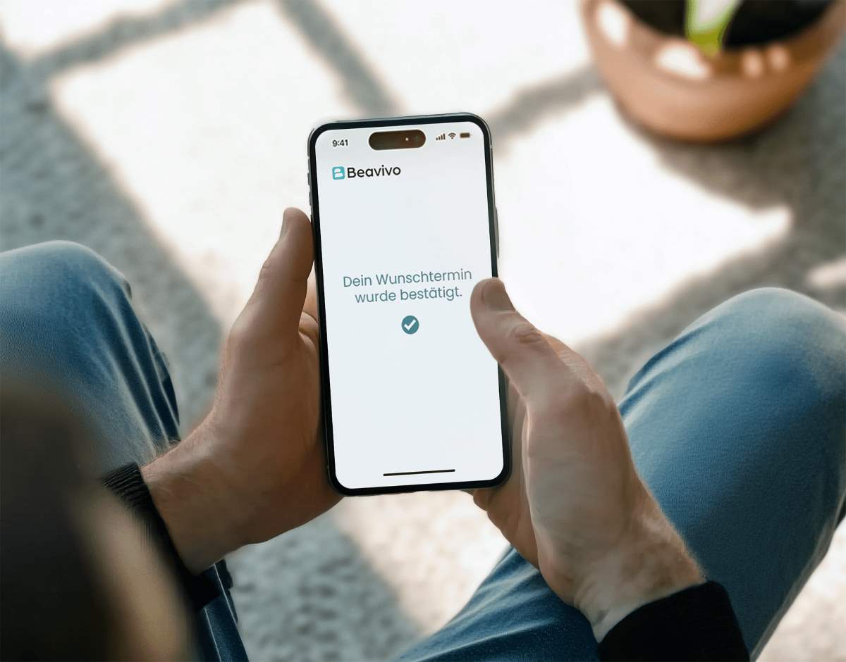 Ein Mann hält ein Smartphone in der Hand. Auf dem Bildschirm ist zu sehen, dass sein Wunschtermin bestätigt wurde.